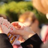 玩法研究员苏晚棠对着屏幕逐局记录蜘蛛纸牌发牌变体结果，旁边摊着写满对照数据的便签纸